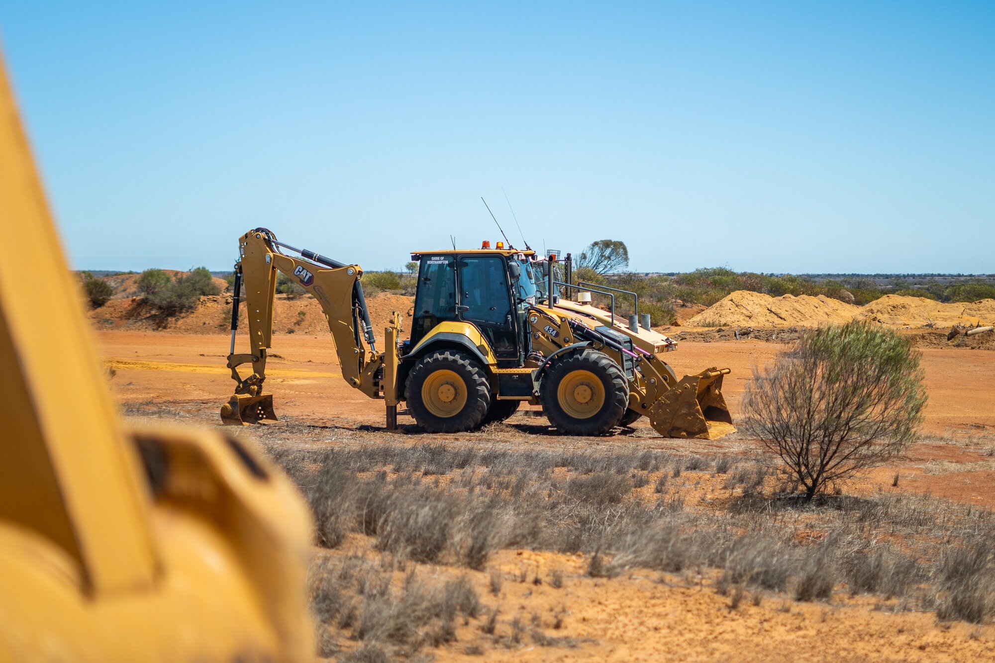 CAT 434 backhoe loader operating on a remote construction site.