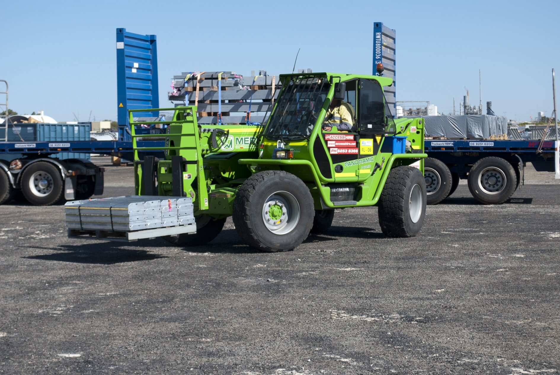 Merlo telehandler transporting bundled construction materials in an industrial yard