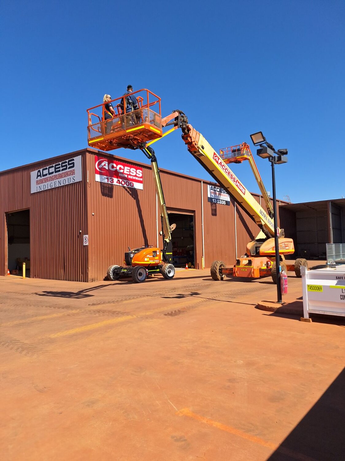 Two Access Hire boom lifts operating outside the Newman branch workshop.