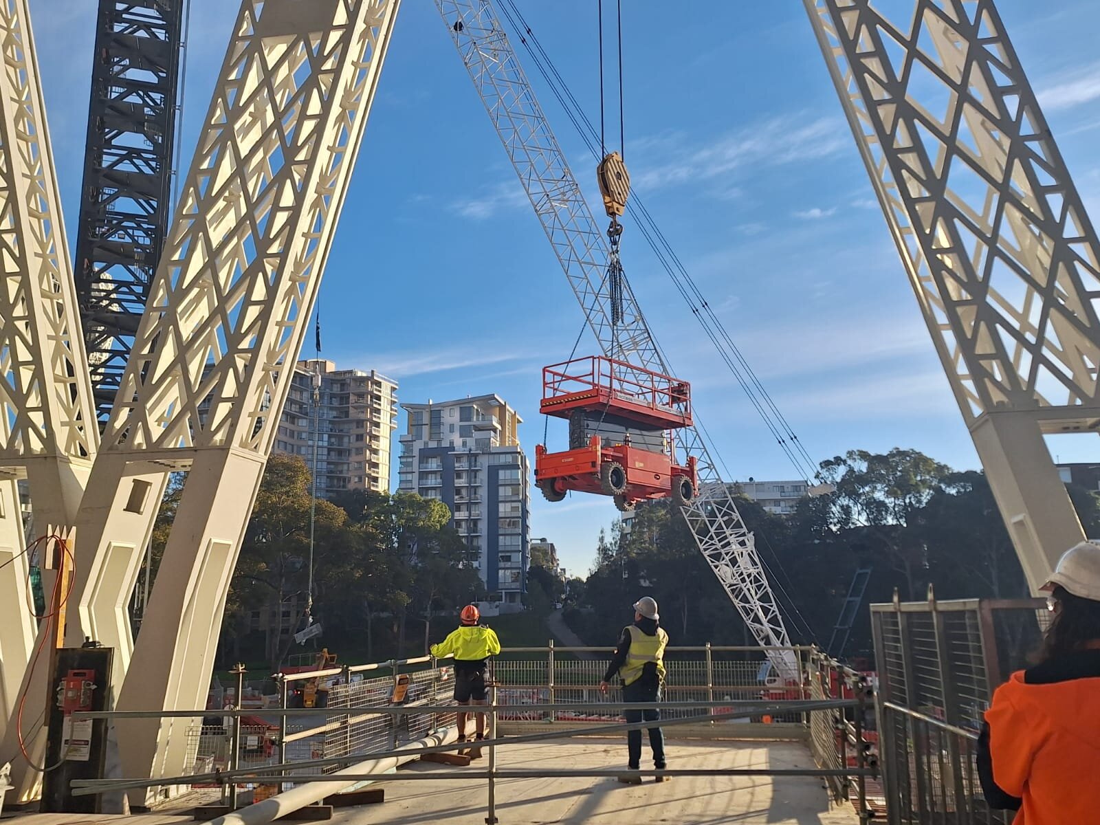 Crane lifting a scissor lift into position on a construction site in New South Wales.