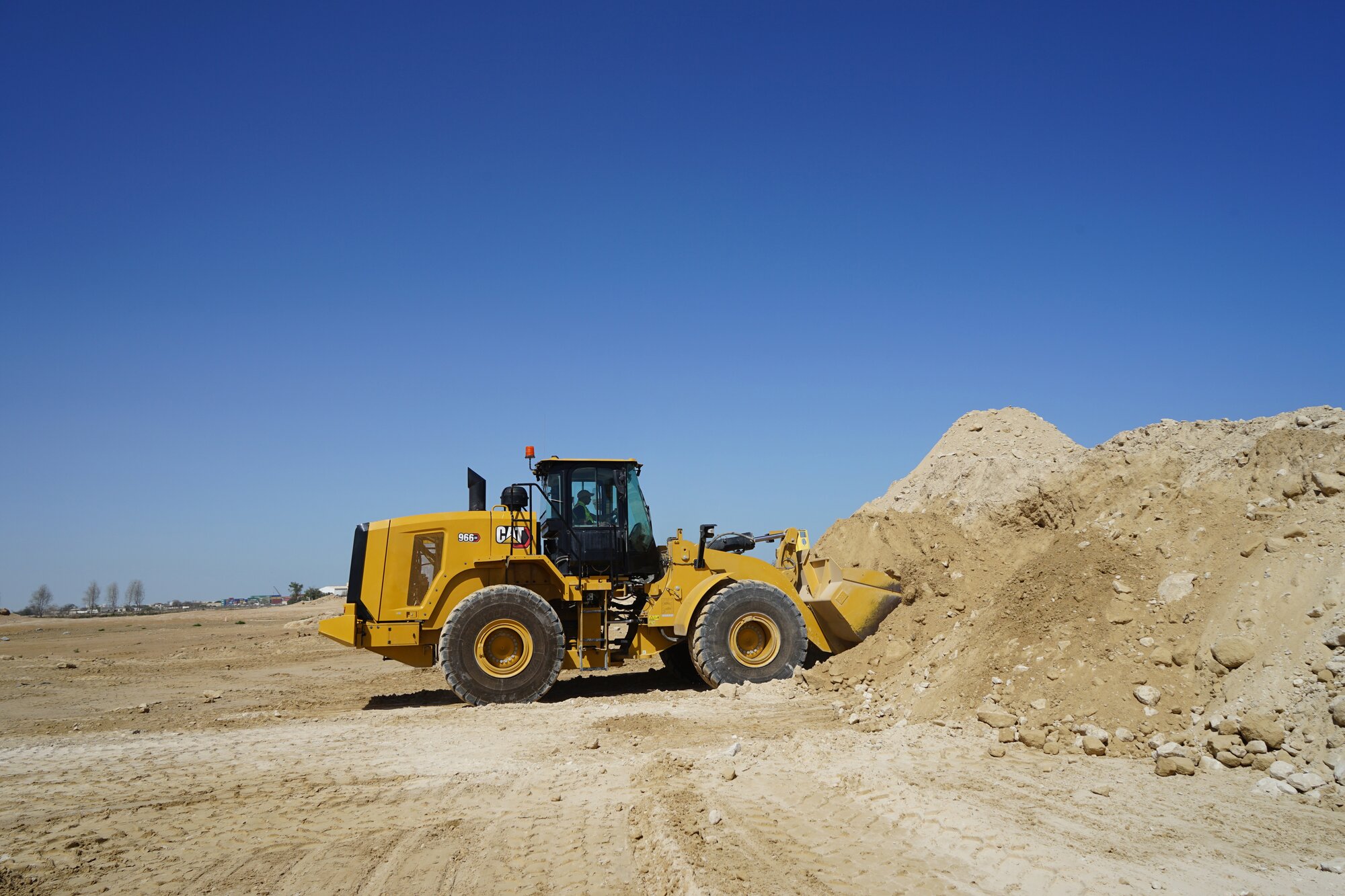CAT 966 wheel loader moving earth on a large construction site.