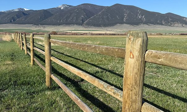 wooden fence post on a clear, sunny day, mountain range in background