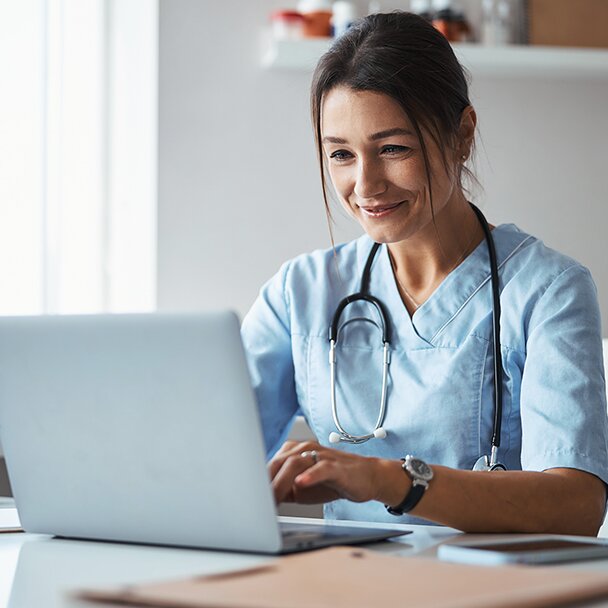 Health care professional sitting at a laptop smiling