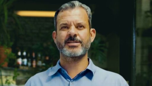 Elisa: Mulher de camisa branca, inclinada sobre o balcão de uma cafeteria 