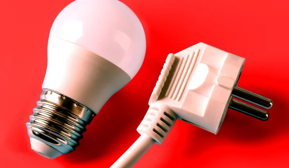 Fotografia de uma lampada ao lado esquerdo e uma tomada ao lado direito, fundo vermelho vivo