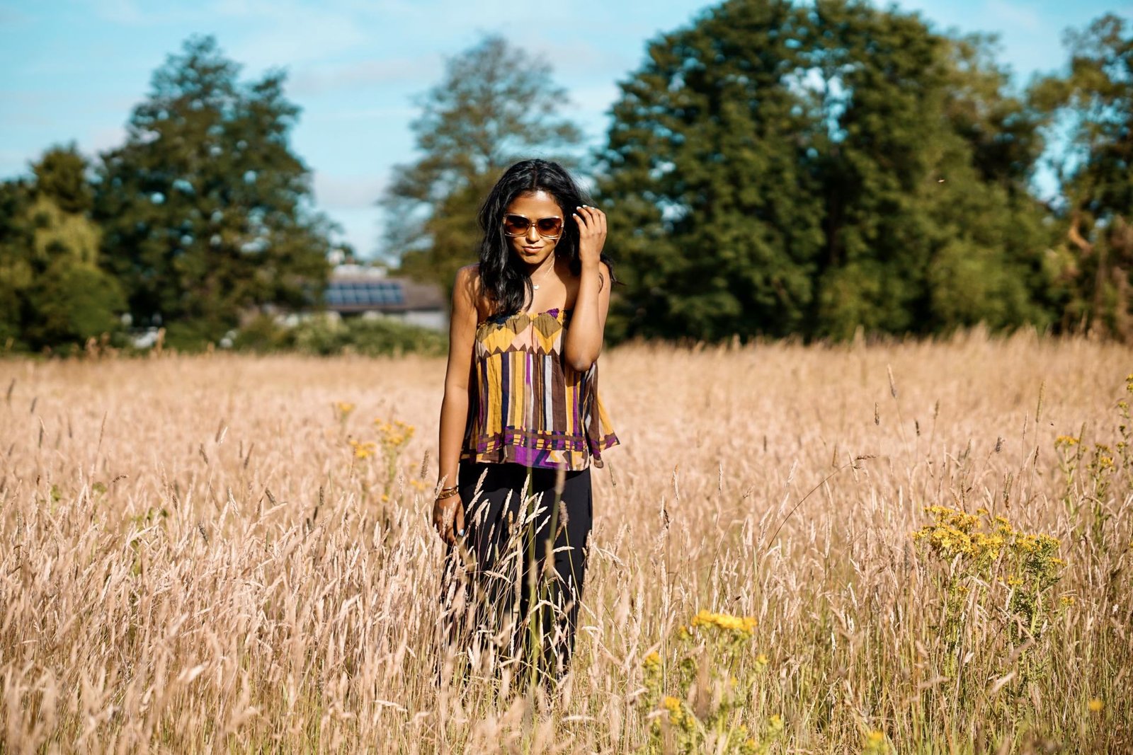 Sachini wearing a Bash dress standing in a field of wheat