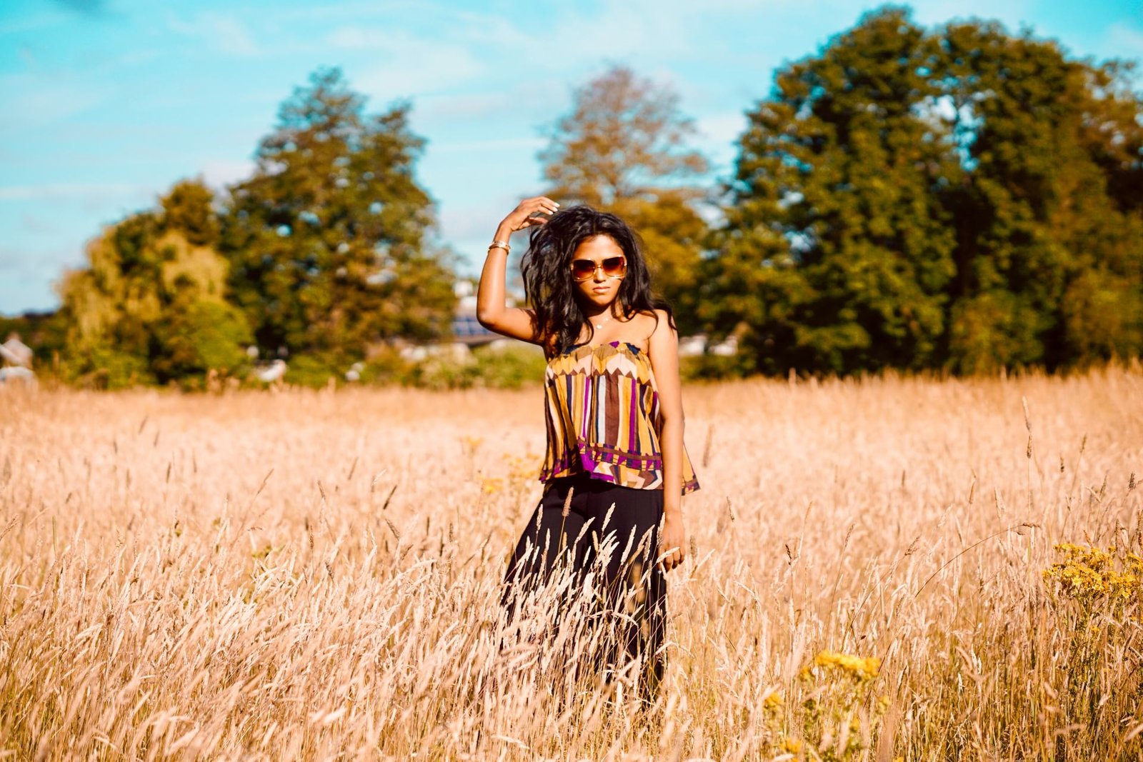 Sachini wearing a Bash dress standing in a field of wheat