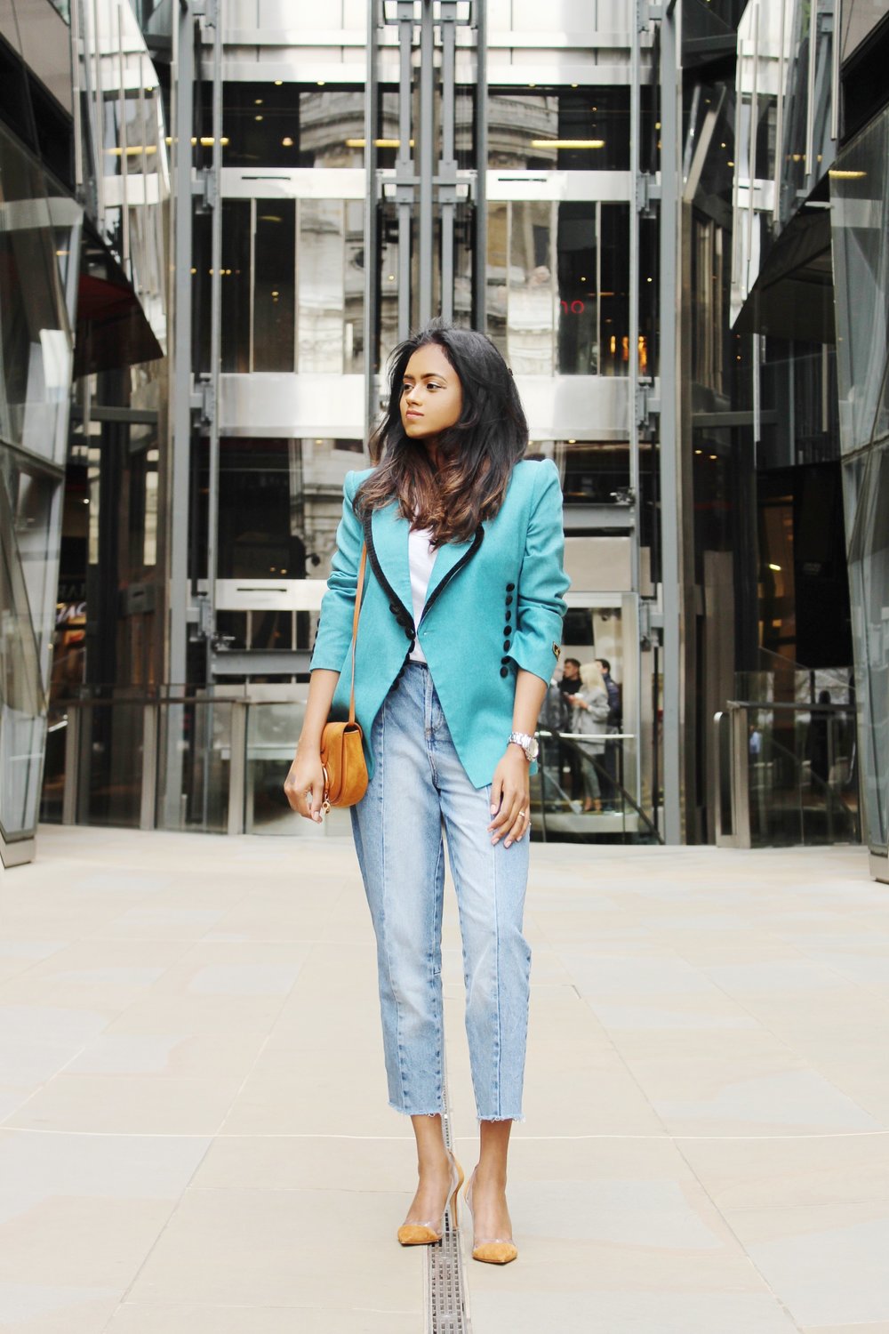 Sachini standing Sachini standing in a shopping street wearing a light blue Fendi vintage blazer, blue jeans and brown Gianvito Rossi heels with a brown handbagin a shopping street wearing a light blue Fendi blazer, blue jeans and brown Gianvito Rossi heels with a brown handbag