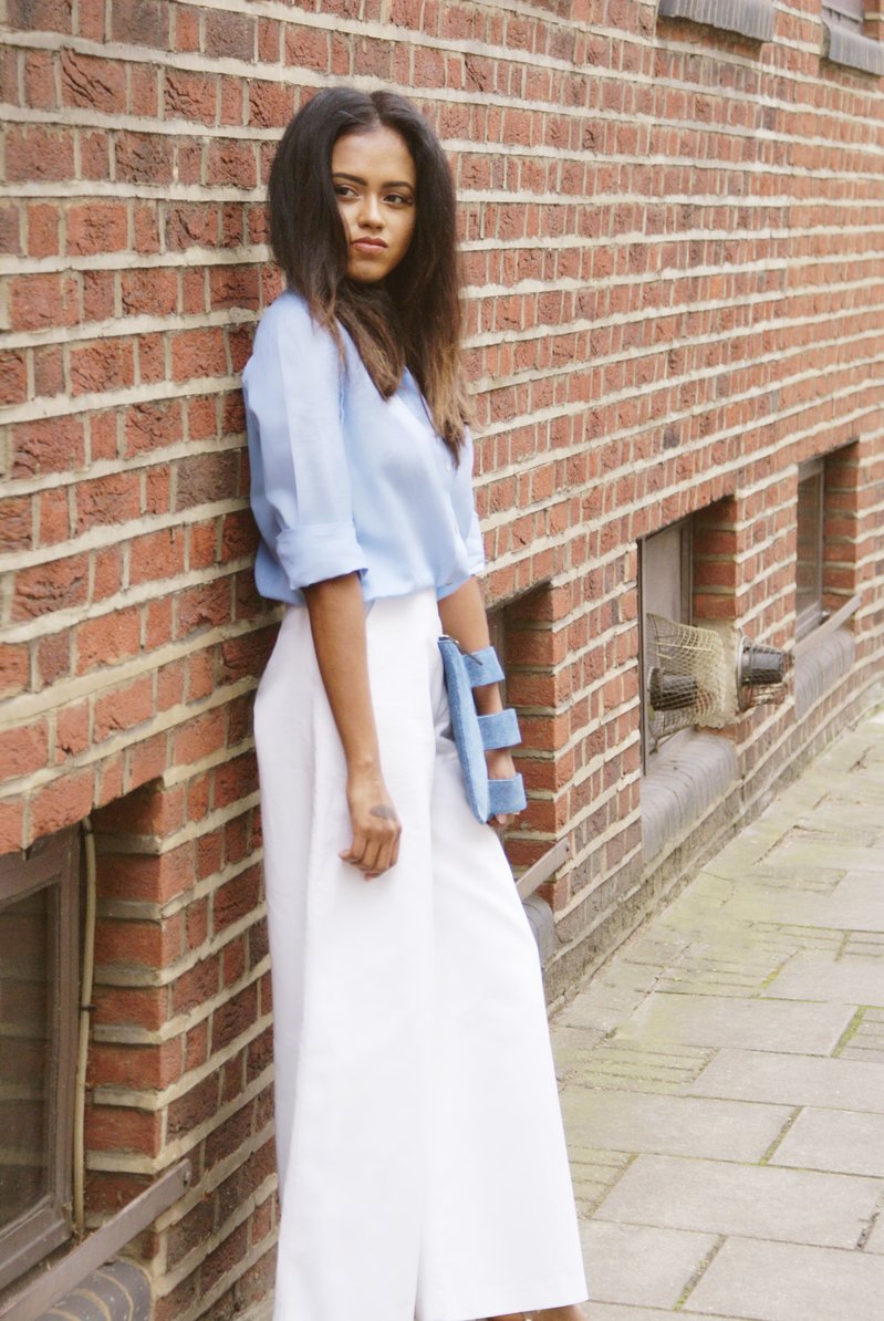 Two pictures of Sachini wearing a blue top, Valentino shoes and white trousers holding a jean colour Embellished Truth bag