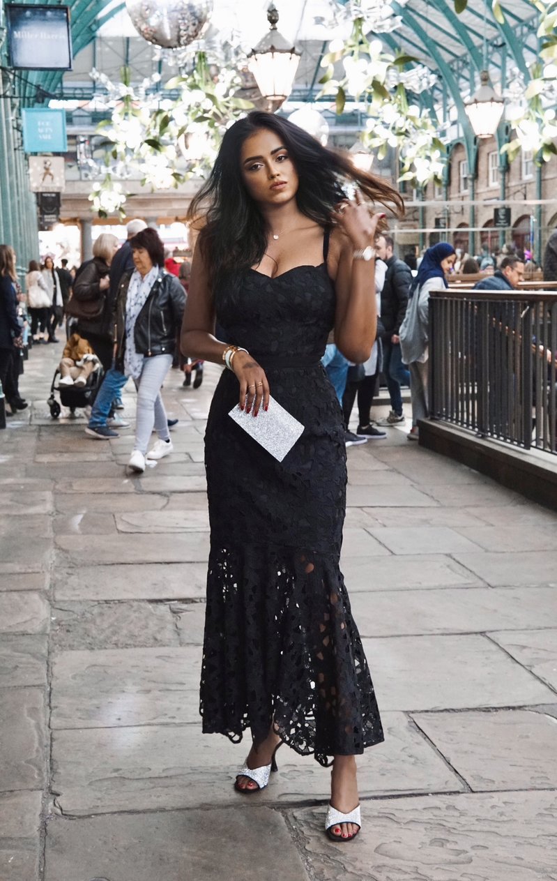 Sachini wearing a black Chi Chi London dress with people walking in the background