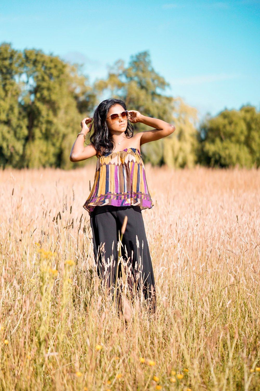 Sachini wearing a Bash dress standing in a field of wheat