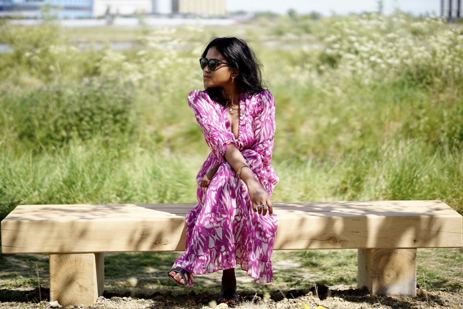 Sachini sitting outdoor wearing a white and pink River Island midi dress