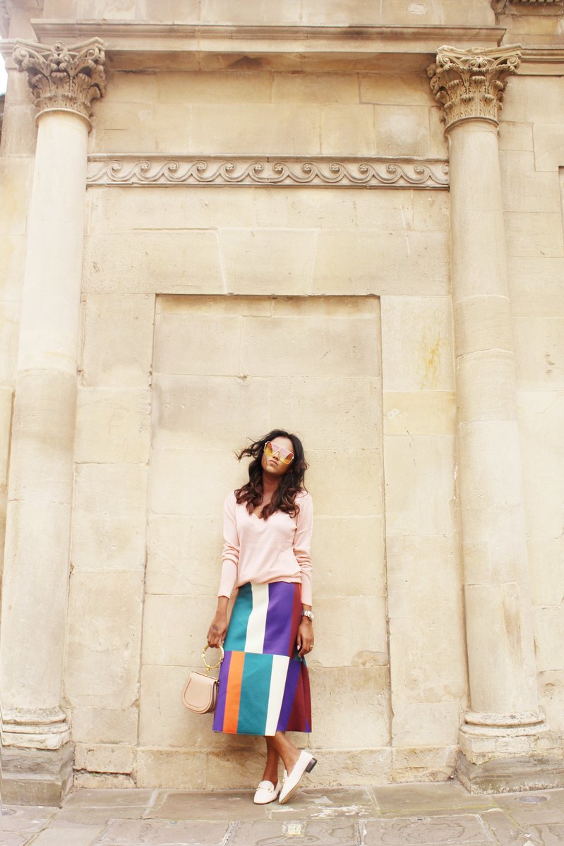 Sachini wearing sunglasses, a pink top and a colour blocked skirt holding a Chloé bag