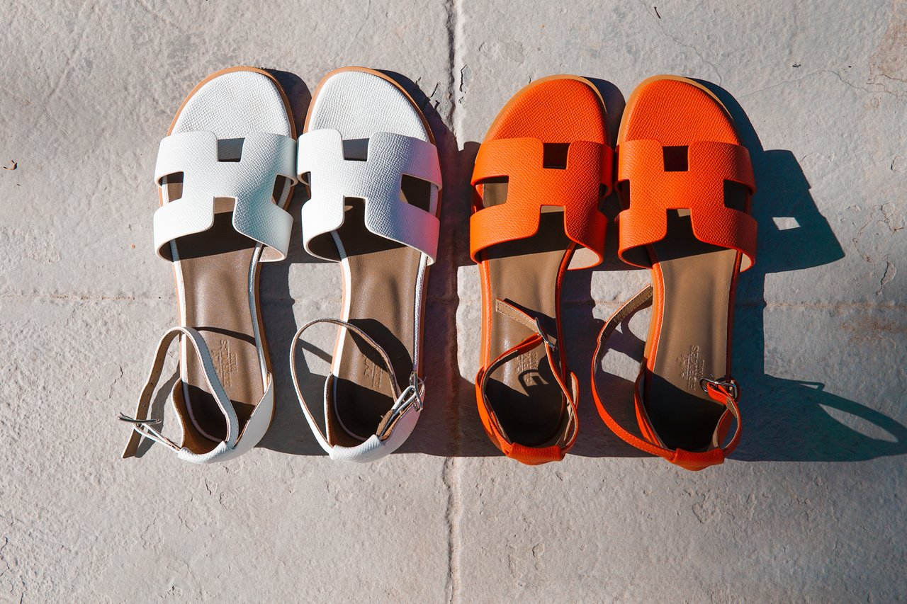 Close up of a white and an orange pair of Hermès sandals