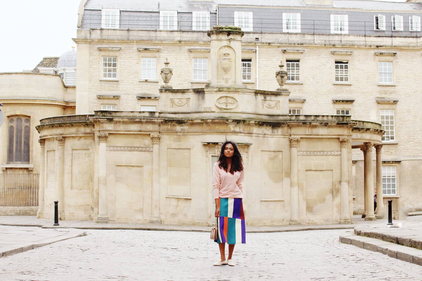 Sachini wearing sunglasses, a pink top and a colour blocked skirt holding a Chloé bag