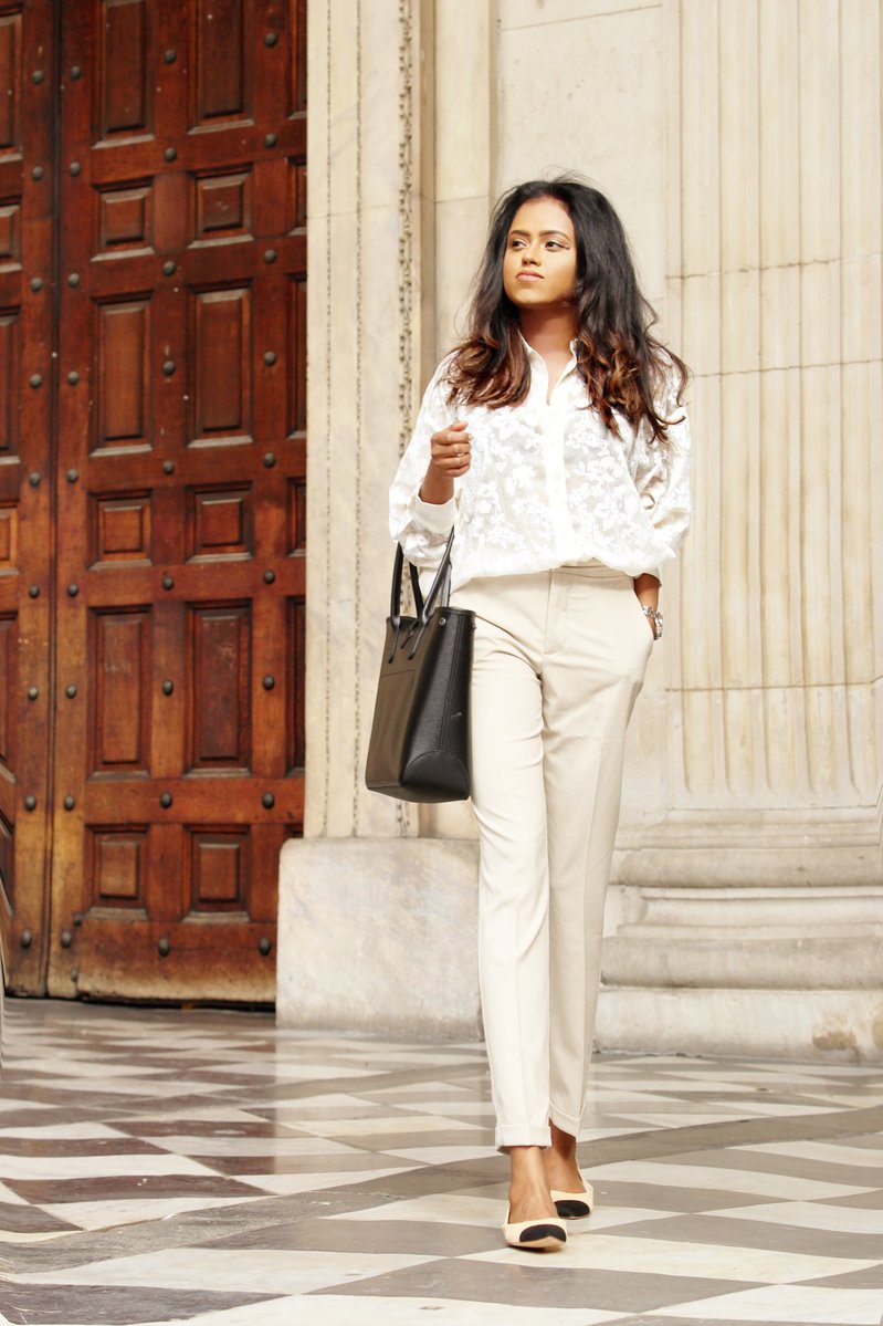 Close up of Sachini wearing a white top and beige trousers 