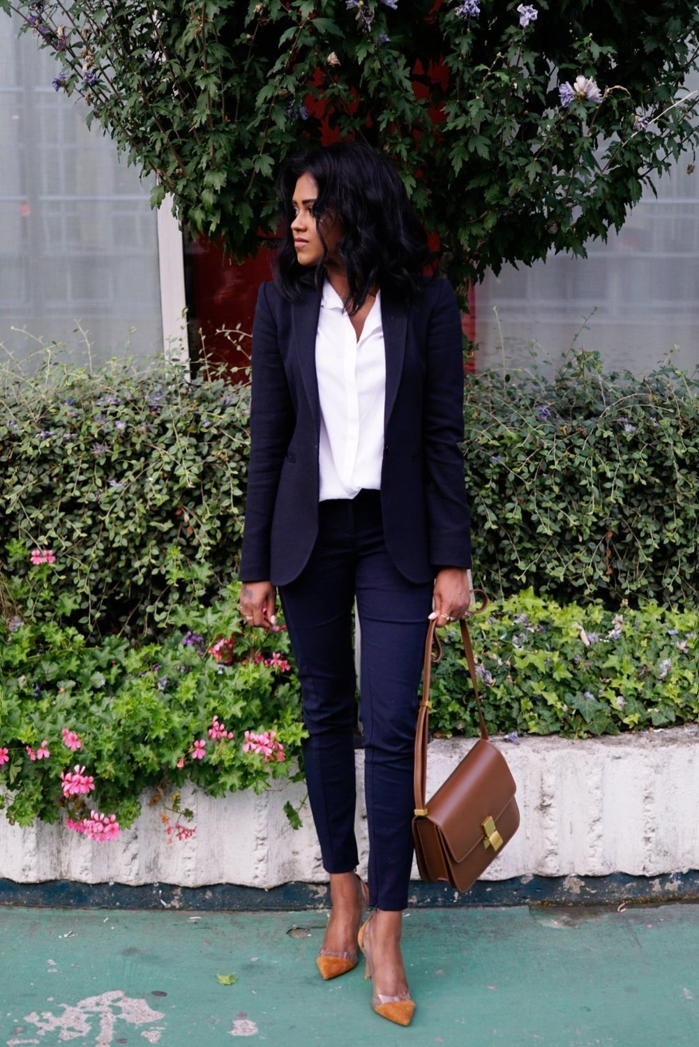 Sachini wearing a black suit and black holding a brown Celine bag