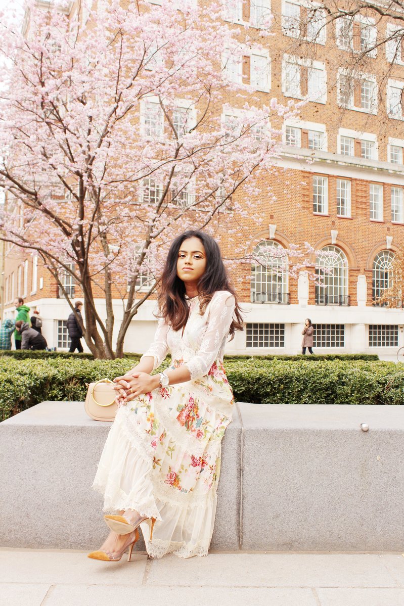 Sachini sitting wearing a floral dress with a Chloé bag