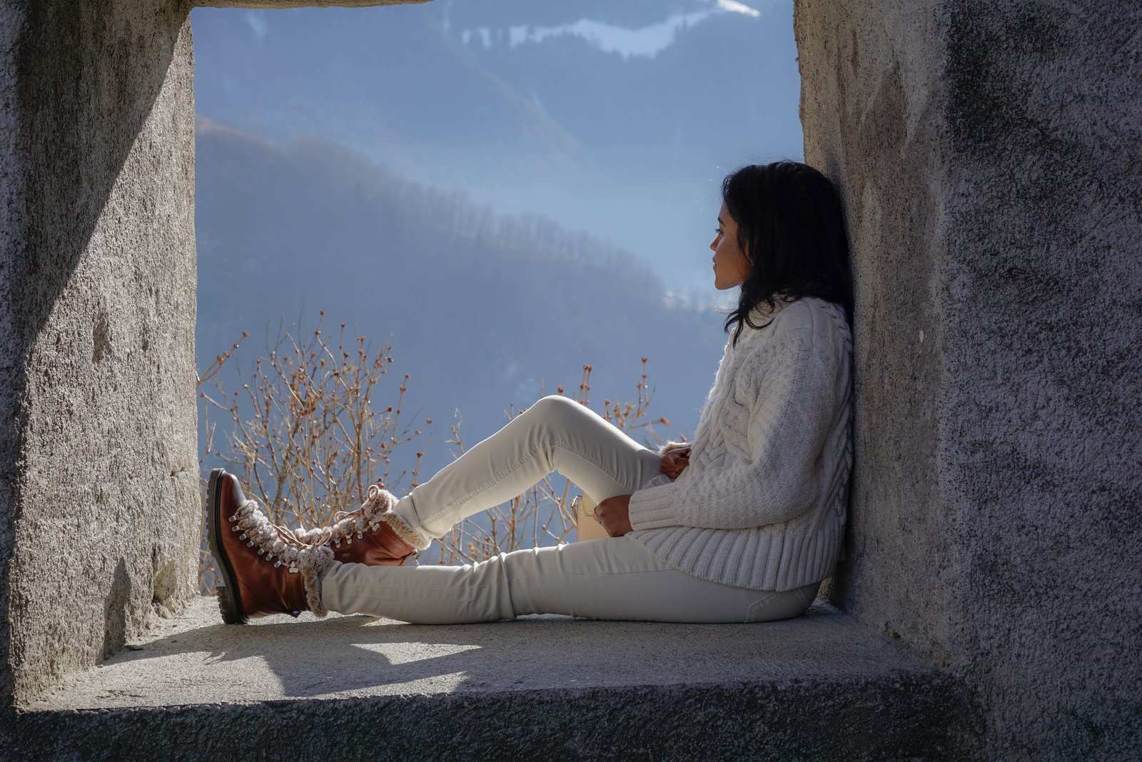 Sachini sitting in a stone window wearing white