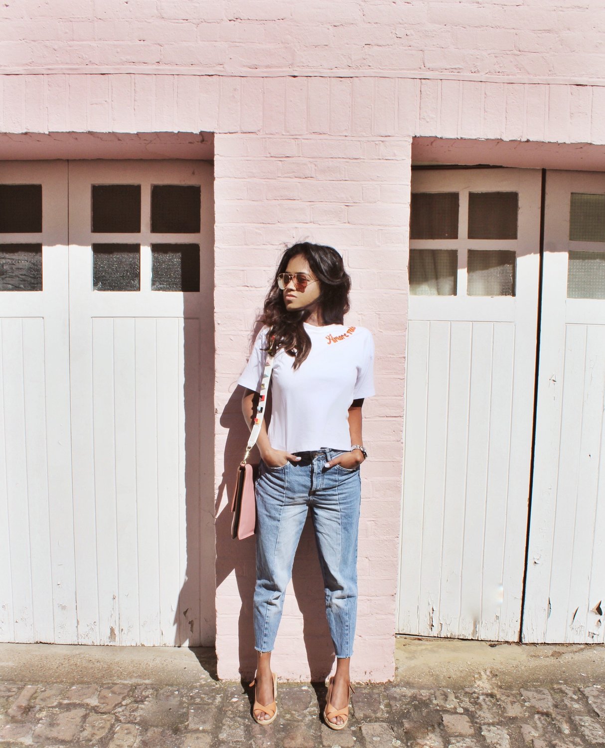 Sachini wearing a white t-shirt, blue jeans with a pink Dolce and Gabanna