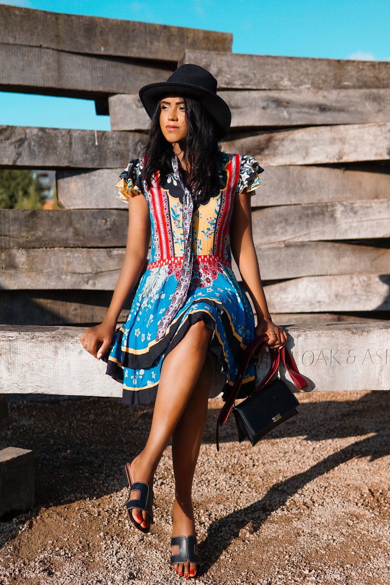 Sachini sitting wearing a Alice and Olivia dress and black hat