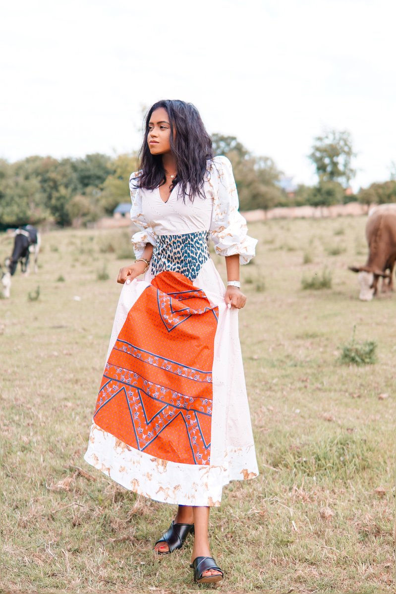 Sachini wearing a Ganni dress with cows in the background