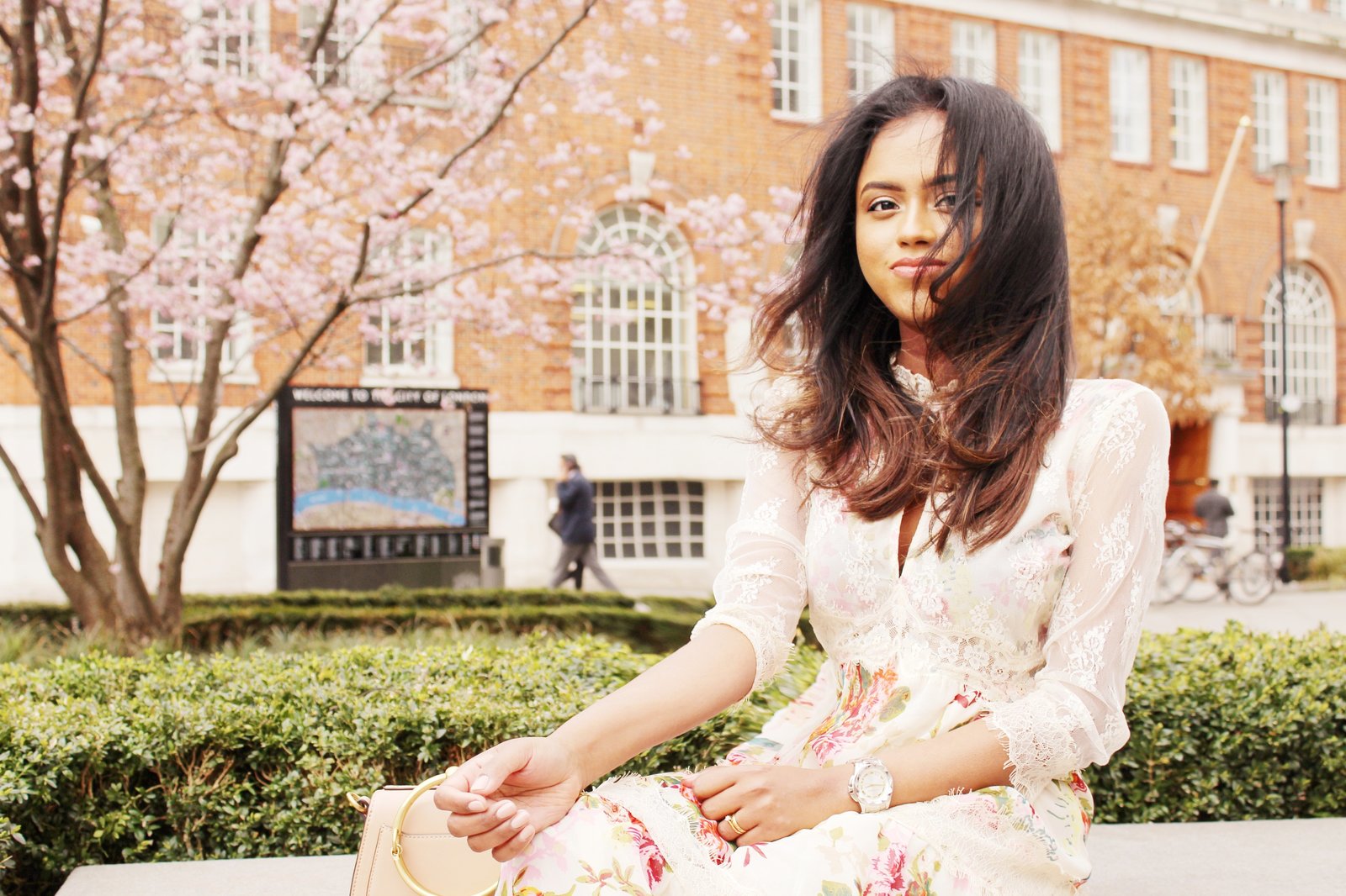 Sachini sitting wearing a floral dress with a Chloé bag