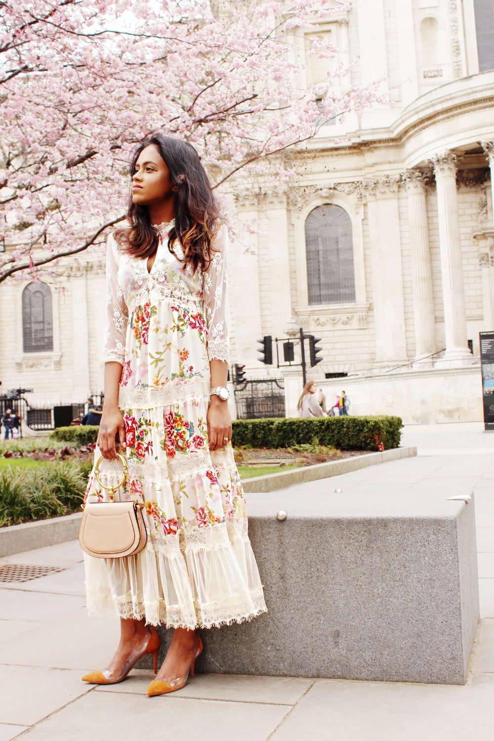 Sachini sitting wearing a floral dress with a Chloé bag