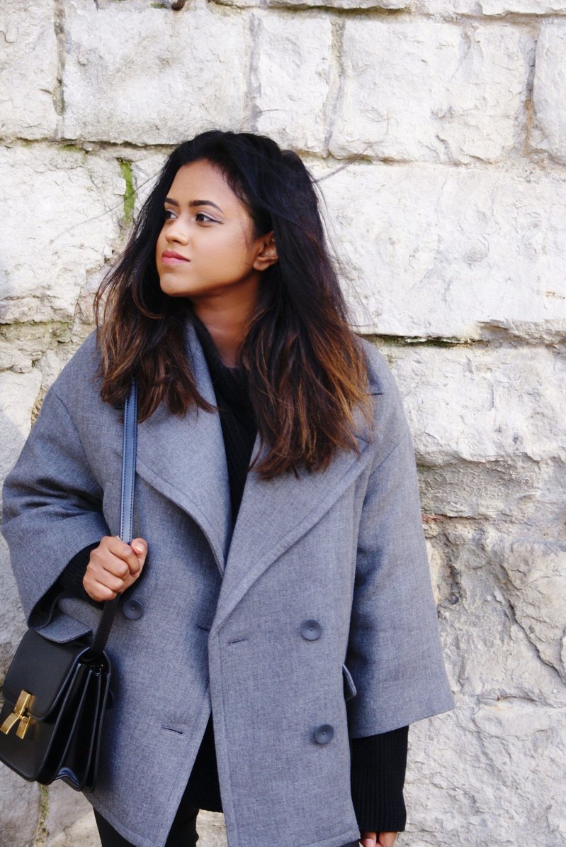 Sachini wearing a grey coat with a black bag