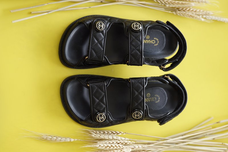 Black Chanel grandpa sandals on a yellow background
