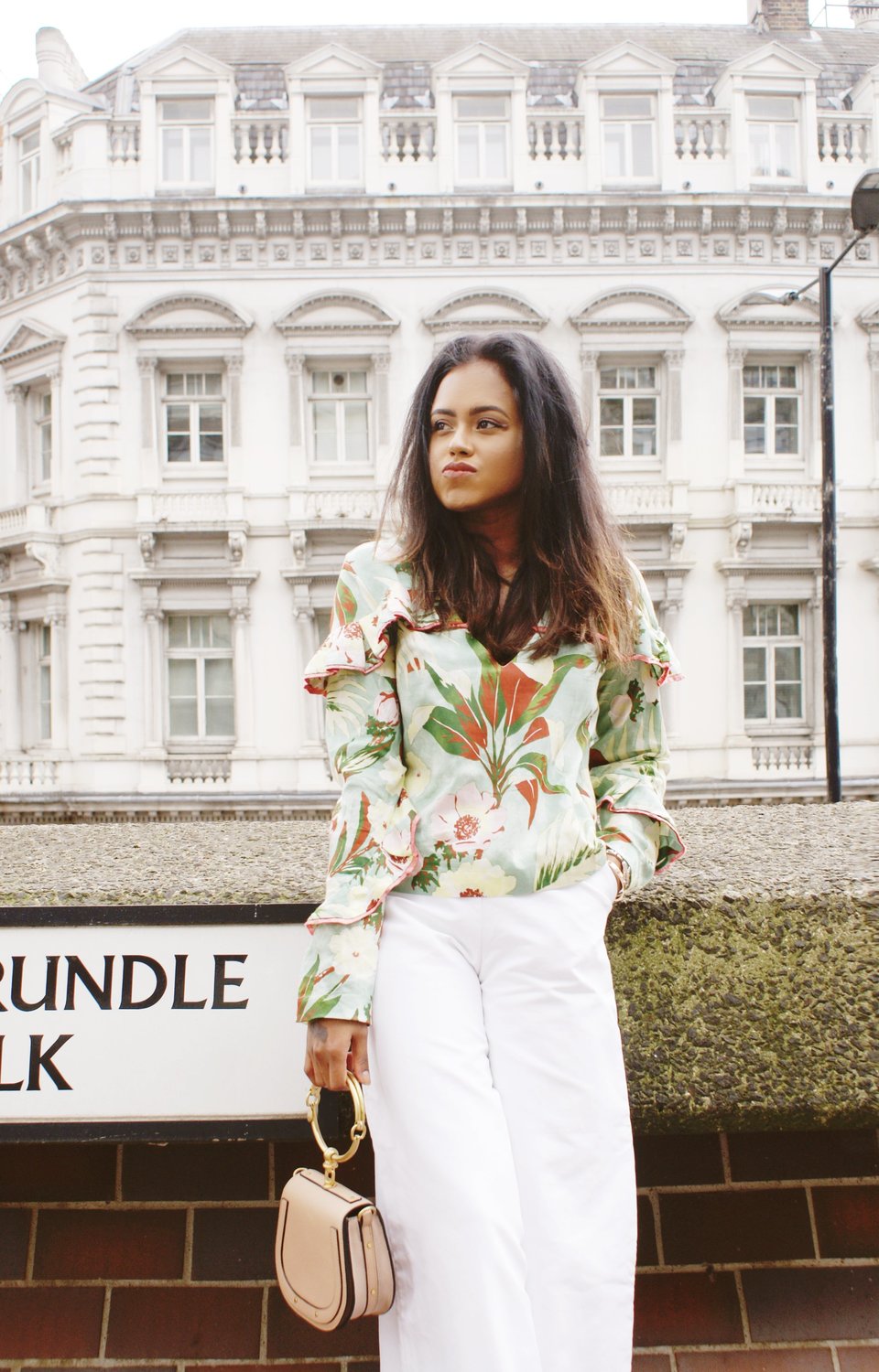 Close up of Sachini wearing a floral top holding a pink Chloé bag