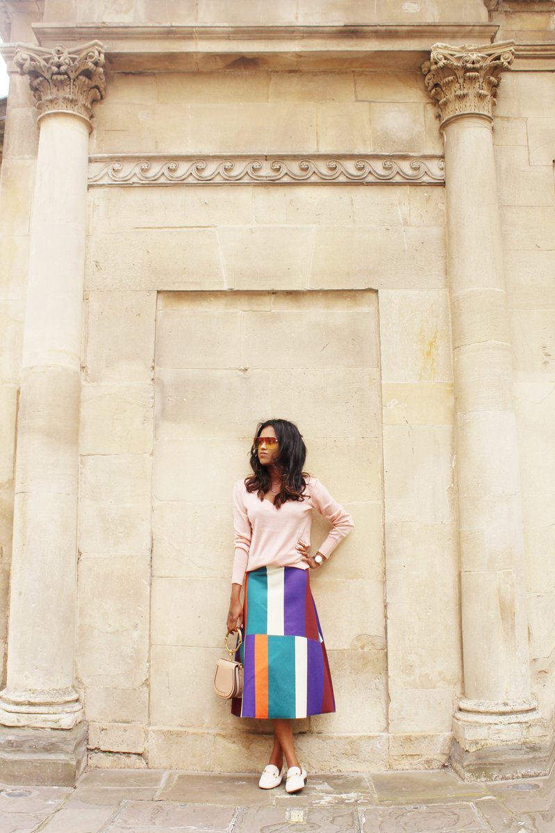 Sachini wearing sunglasses, a pink top and a colour blocked skirt holding a Chloé bag