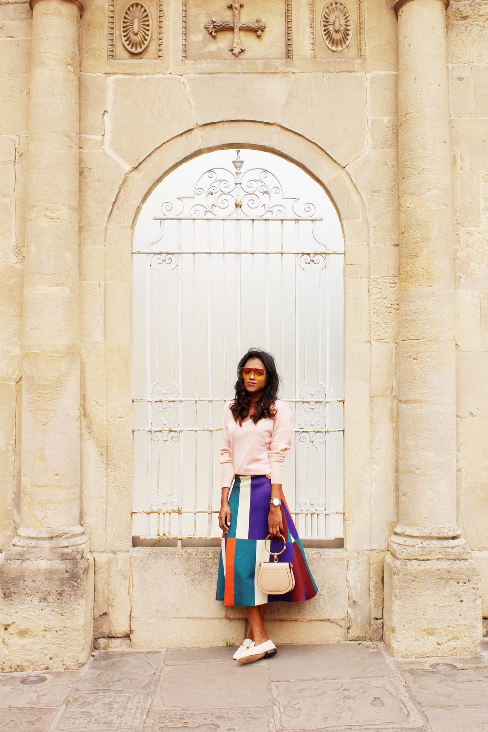 Sachini wearing sunglasses, a pink top and a colour blocked skirt