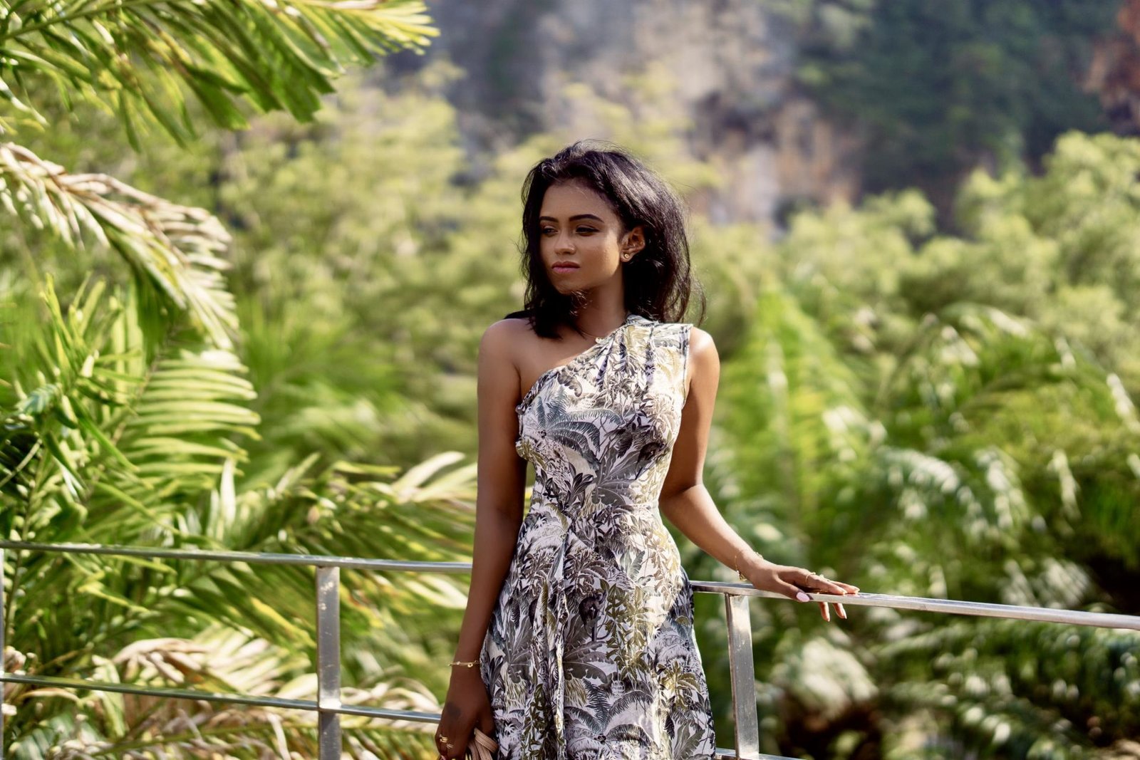 Sachini wearing a white and green Reiss dress with exotic trees in the background