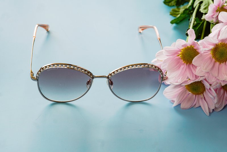 close up of Chanel cat-eye sunglasses  next to  pink flowers