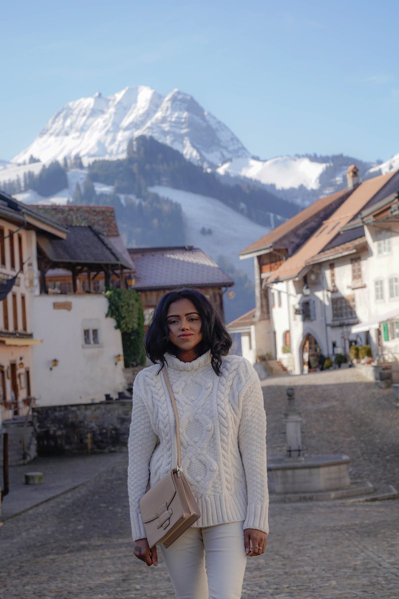 Sachini wearing white in a village with a mountain in the background