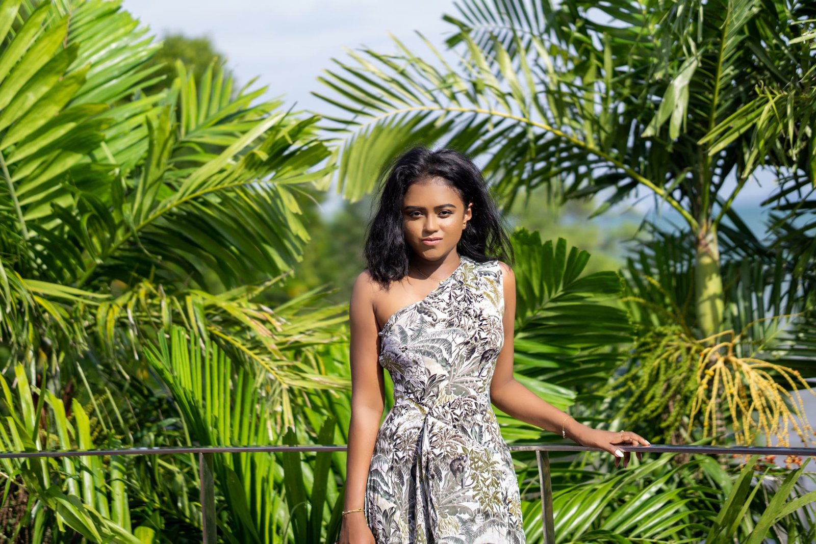 Sachini wearing a white and green Reiss dress with  exotic trees in the background