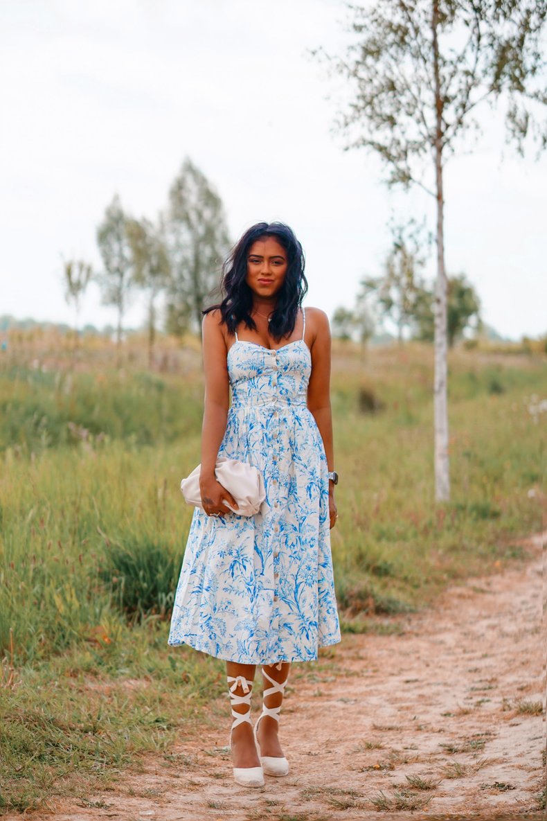 Sachini wearing a white and blue dress in a field 