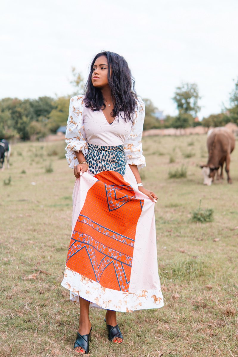 Sachini wearing a Ganni dress with cows in the background