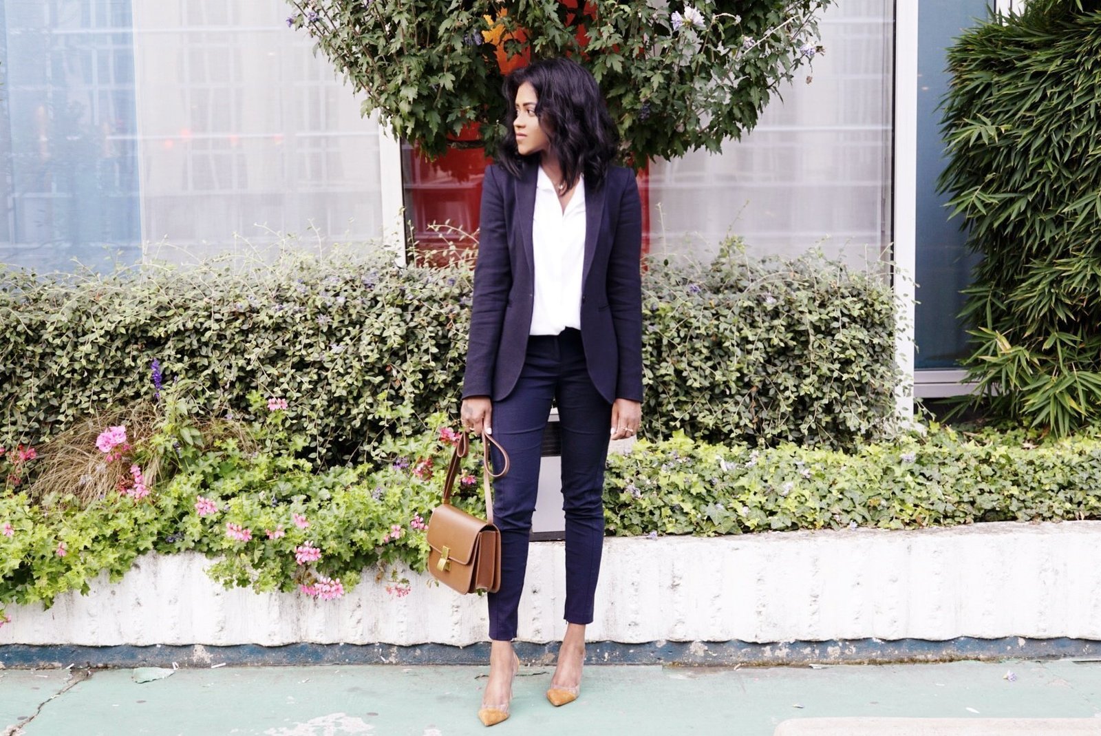 Sachini wearing a black suit and black holding a brown Celine bag