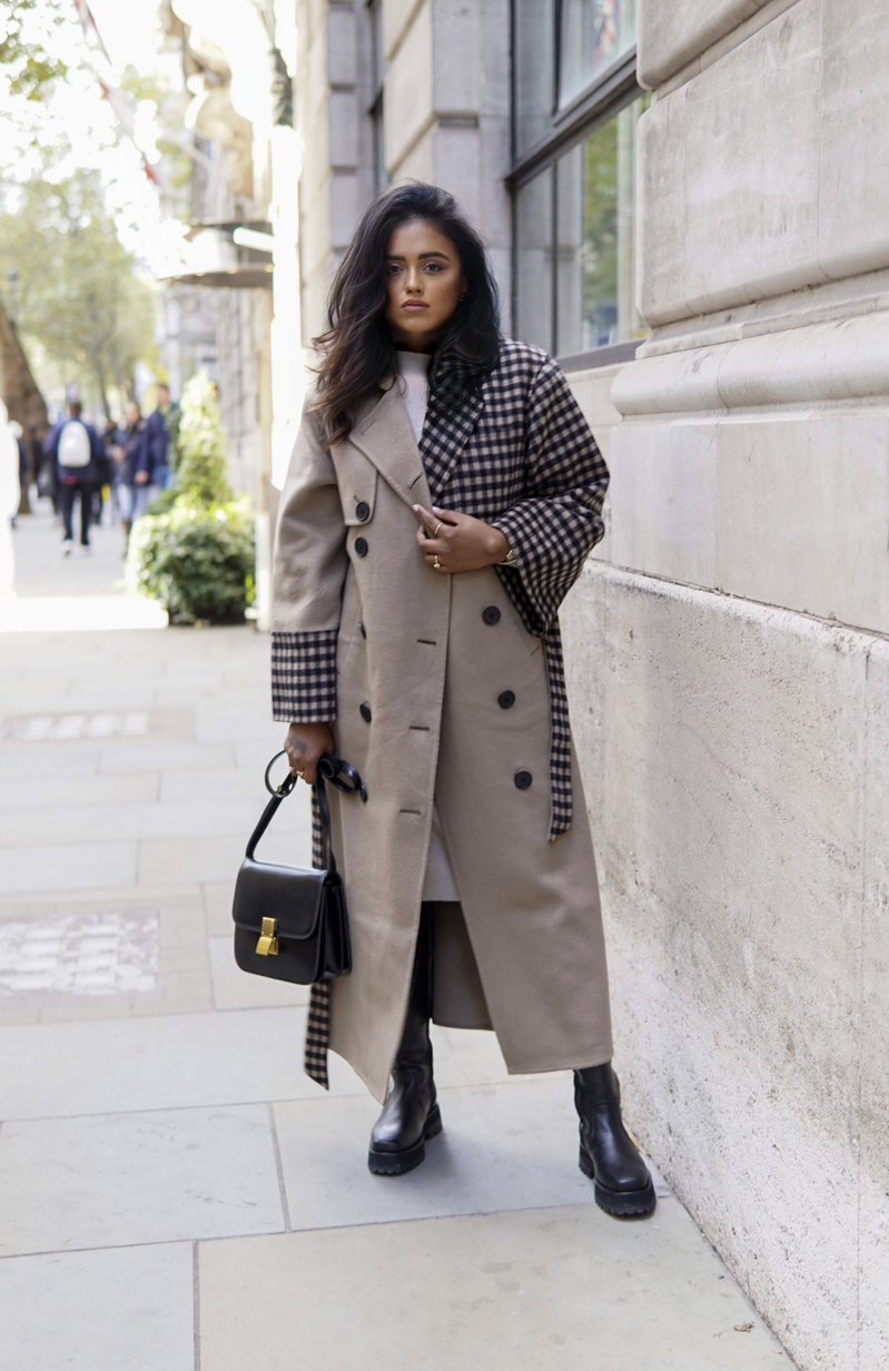 Sachini standing on a sidewalk wearing a QUAINT Josephine Coat holding a black Dior saddle bag