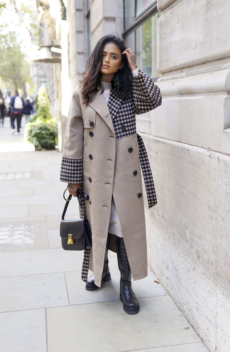 Sachini standing on a sidewalk wearing a QUAINT Josephine Coat holding a black Dior saddle bag