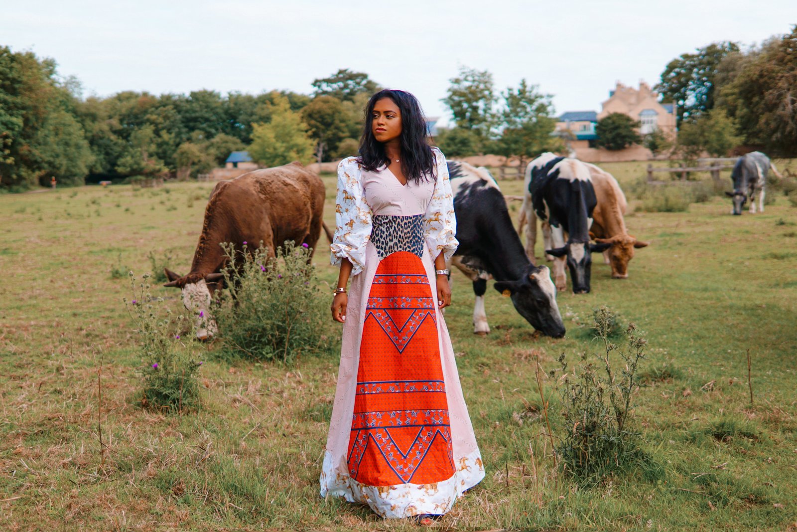 Sachini wearing a Ganni dress with cows in the background