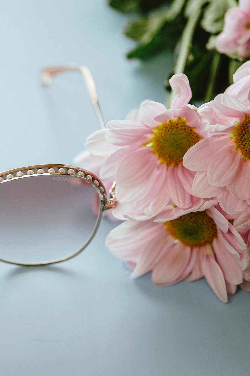 close up of Chanel cat-eye sunglasses  next to  pink flowers