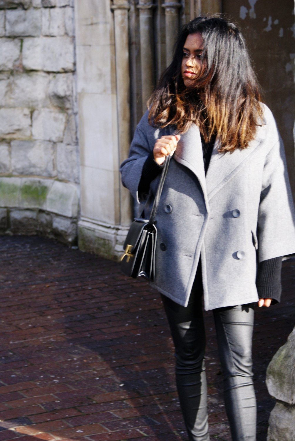 Sachini wearing a grey coat, black trousers with a black bag