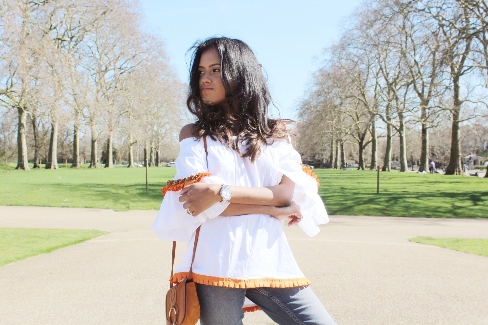 Close up of Sachini wearing a white top, blue jeans with a brown handbag