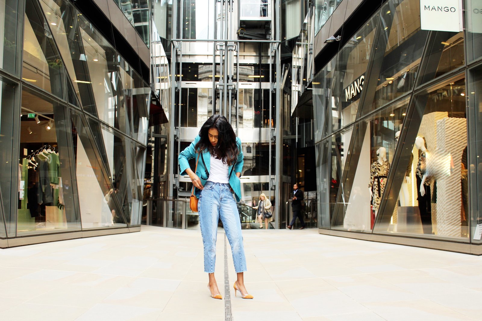 Sachini standing in a shopping street wearing a light blue Fendi vintage blazer, blue jeans and brown Gianvito Rossi heels with a brown handbag