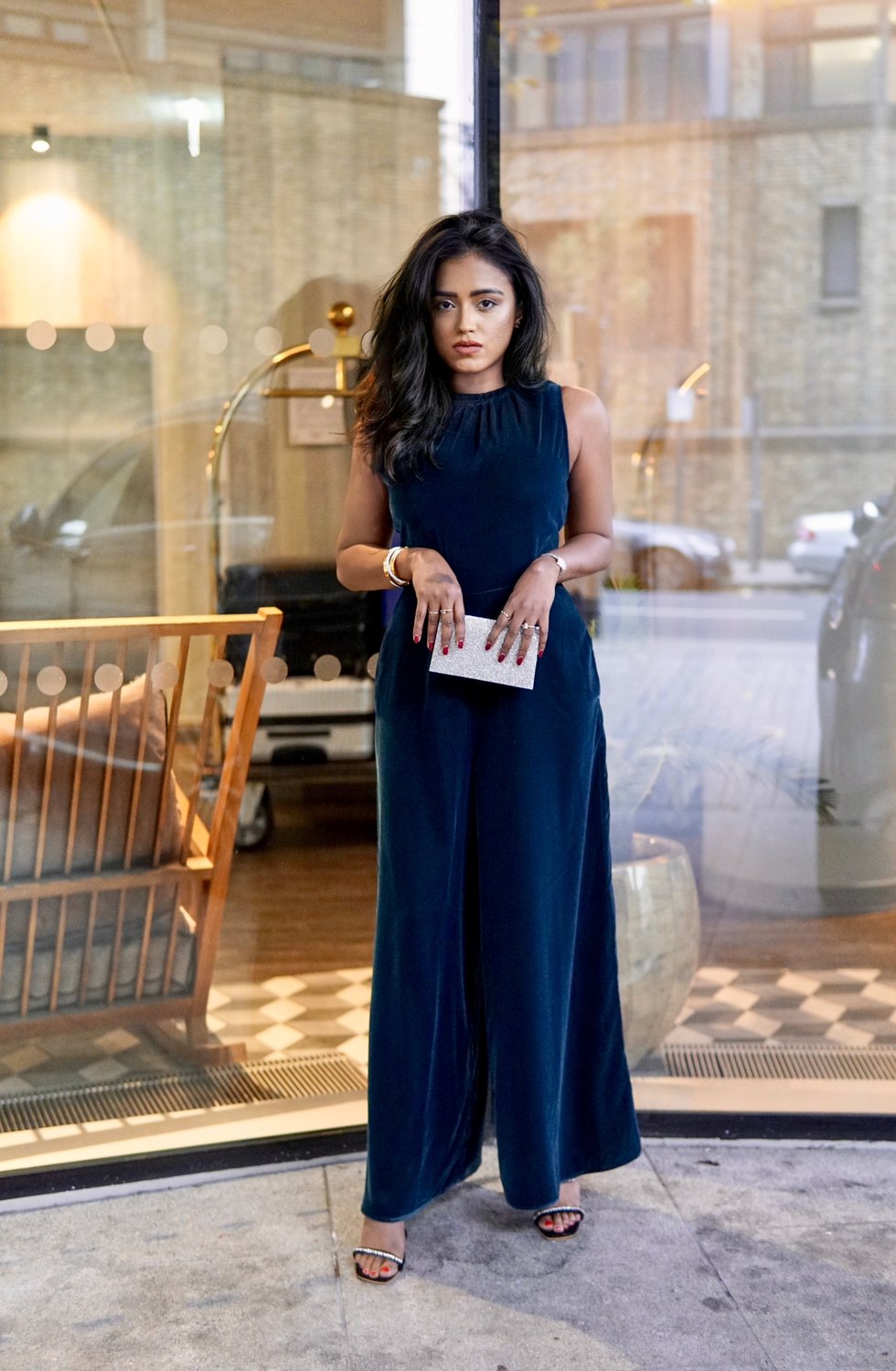 Sachini standing in front of a glass window wearing a navy colour Albaray dress holding a small silver handbag