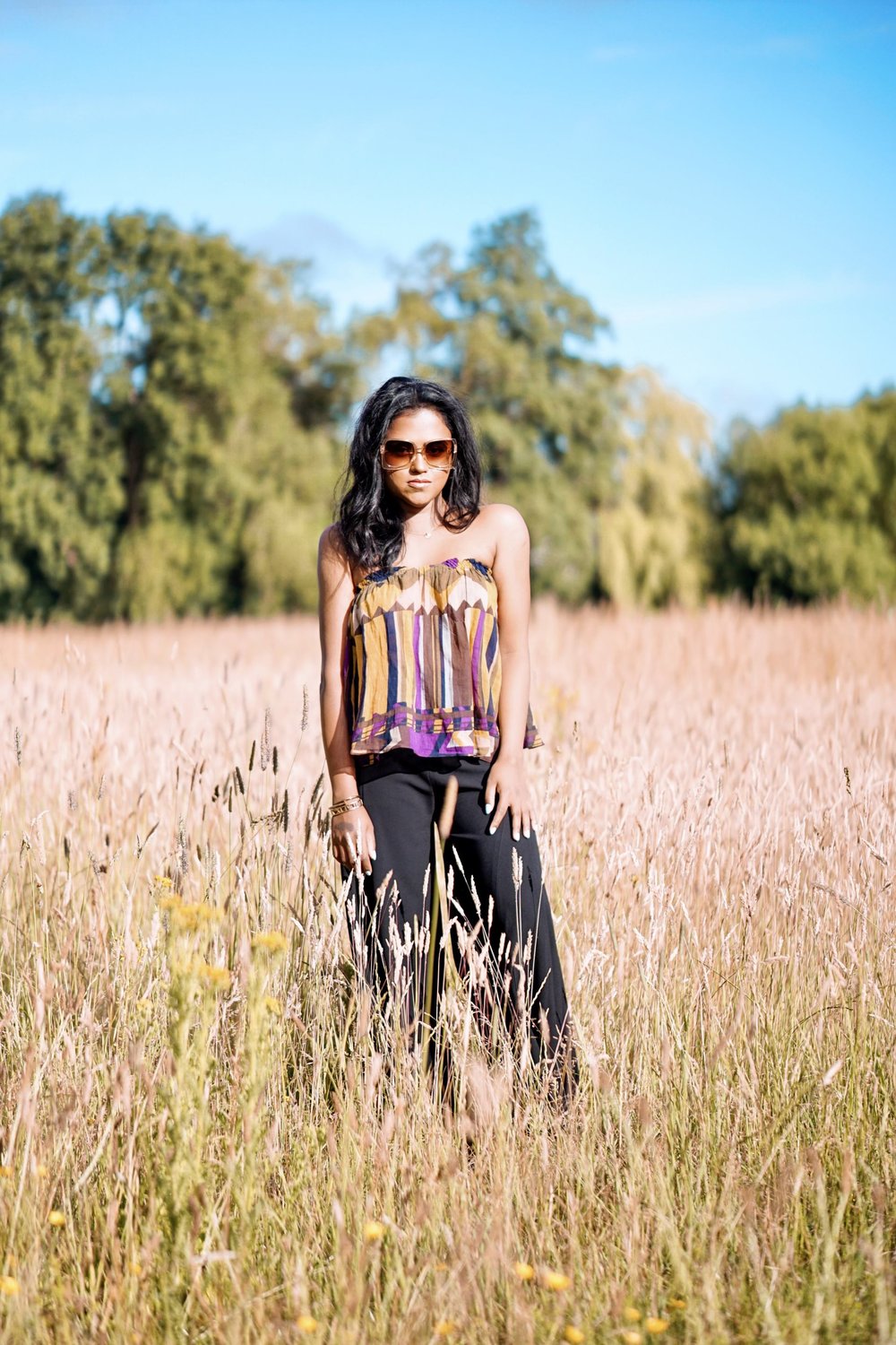 Sachini wearing a Bash dress standing in a field of wheat
