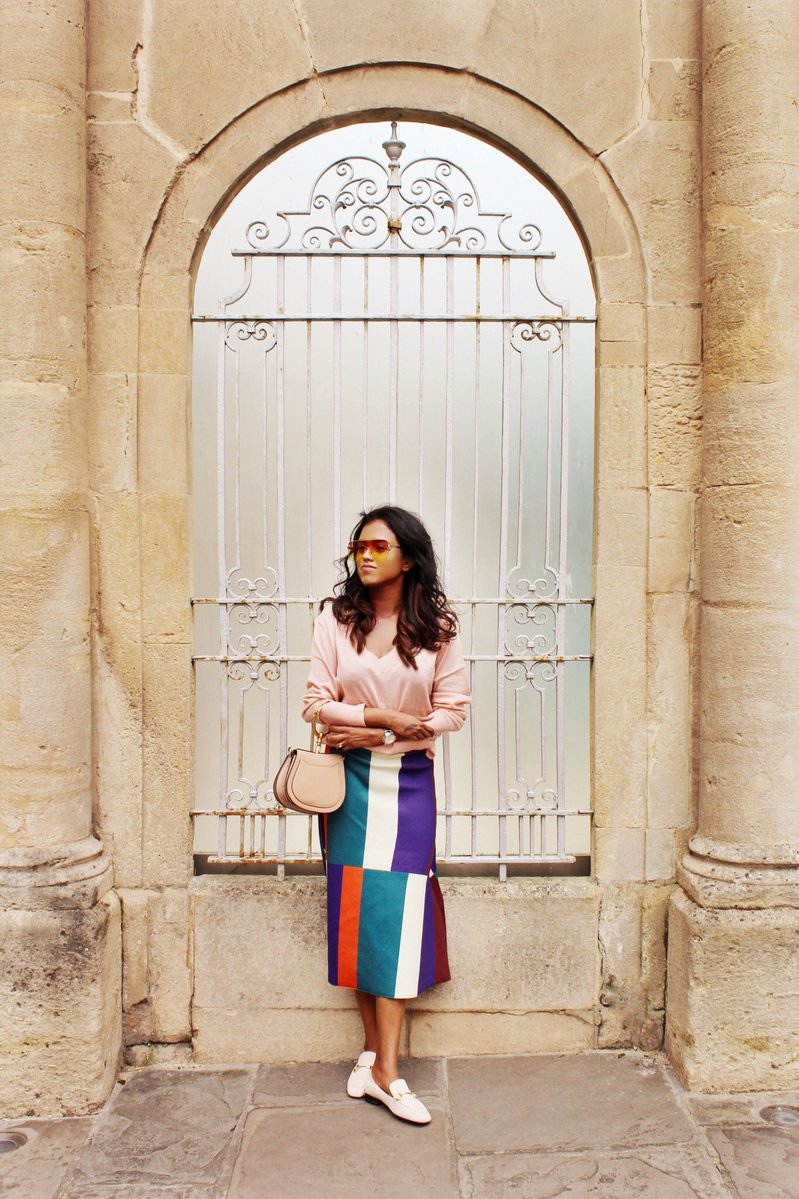 Sachini wearing sunglasses, a pink top and a colour blocked skirt holding a Chloé bag